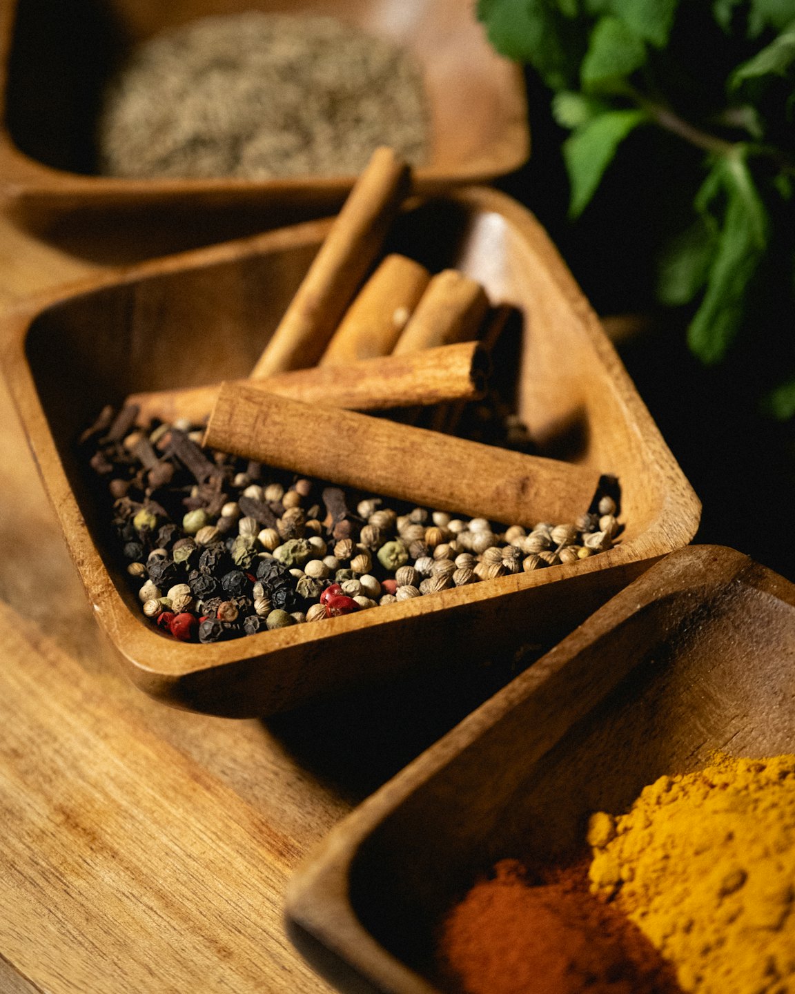 Colorful spices arranged in small wooden bowls on a table.