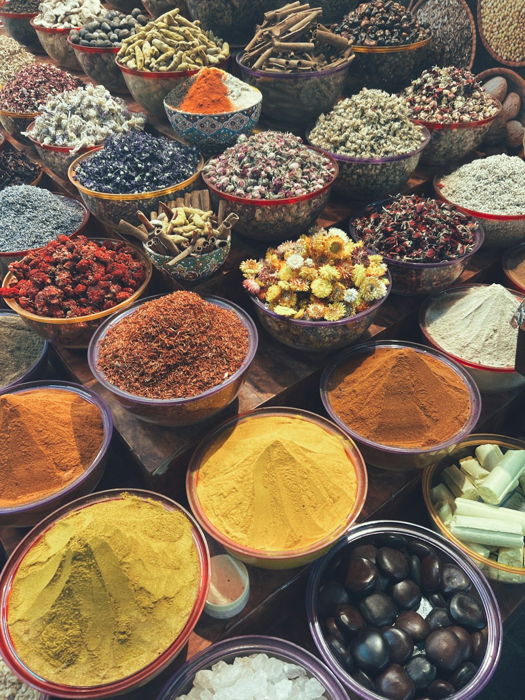 Various dried spices and herbs in small bowls on wood.