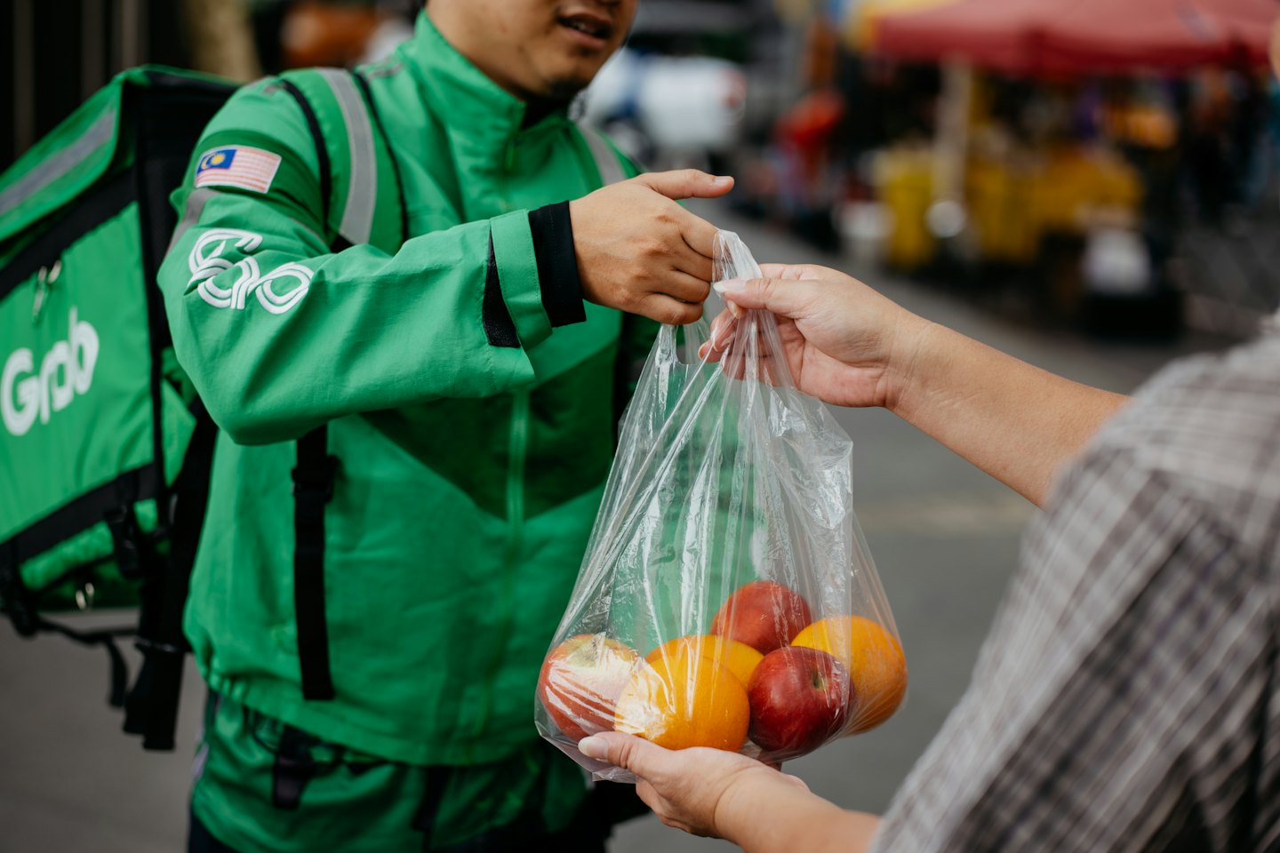 Delivery driver hands bag of fruit to customer.