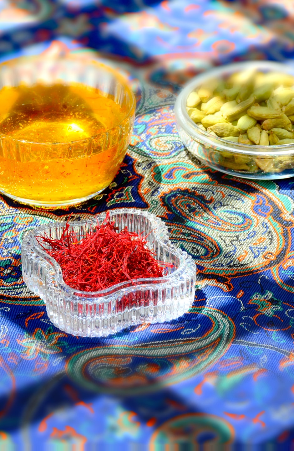 Three bowls of spices rest on a paisley patterned tablecloth.